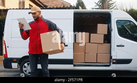 Young man using tablet to view information about the parcel. Delivering the package. High quality photo Stock Photo