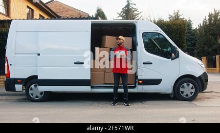 Young delivery man using tablet to find the address and deliver parcel. High quality photo Stock Photo