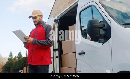 Young delivery man using tablet to find the address and deliver parcel. High quality photo Stock Photo
