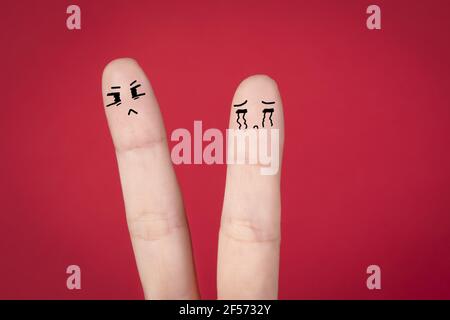 Closeup of an angry couple doodle on fingers against a red background Stock Photo