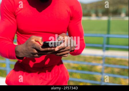 Close-up black unrecognizable man holding smartphone. guy in sport clothing. Stock Photo