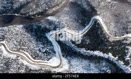 Aerial view of the river and taiga forests and road in the winter - springtime . Abstract landscape of northern nature with drone. Stock Photo