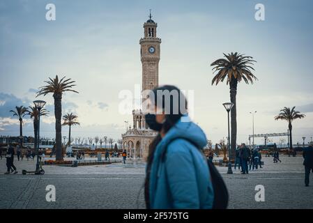 Izmir, Turkey - March 23 2021: Blurred woman with mask walks in the Konak square. Izmir Clock Tower. Stock Photo