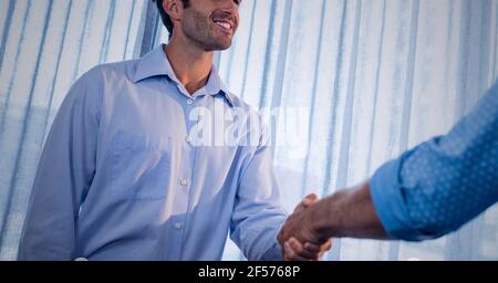Businessmen smiling and shaking hands in office Stock Photo