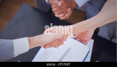Businesswomen shaking hands over desk in office Stock Photo