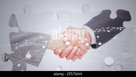 Composition of businessman and businesswoman shaking hands with network of connections and puzzles Stock Photo