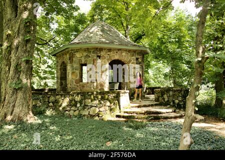 Woman standing in front of stone building in garden at Greenwood Gardens, in Short Hills, NJ Stock Photo