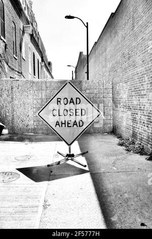 Road Closed Ahead sign. Blocked alleyway with brick buildings on either side. Stock Photo