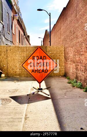 Road Closed Ahead sign. Blocked alleyway with brick buildings on either side. Stock Photo