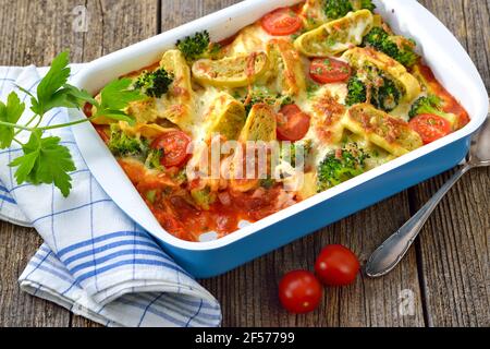 Vegetarian casserole with cut Swabian vegetable ravioli, tomatoes, broccoli and cheese served hot from the oven Stock Photo
