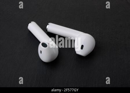 Pair of white true wireless earbuds on black stone background Stock Photo