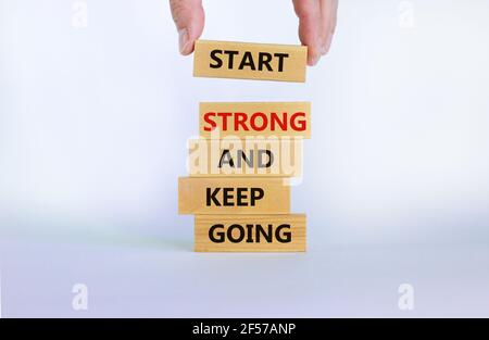 Start strong and keep going symbol. Concept words 'Start strong and keep going' on wooden blocks on a beautiful white background. Businessman hand. Bu Stock Photo