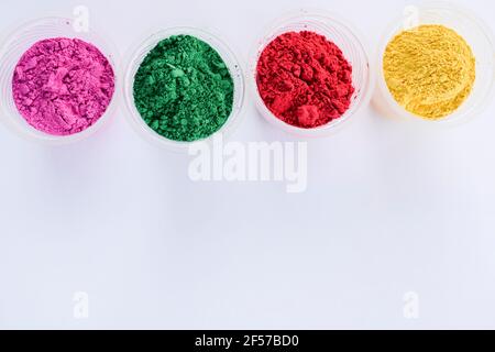 Organic colors in bowl used during Indian holi festivals. Holi colour powders vibrant pink, red, gren and yellow. White background blank space to writ Stock Photo