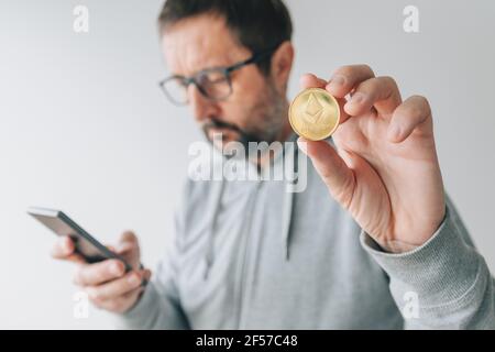 Cryptocurrency trader checking Ethereum price online using mobile smart phone, close up with selective focus Stock Photo