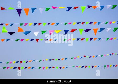 triangular festive multi-colored flags are suspended on a tight rope against the background of the sky, nobody. Stock Photo