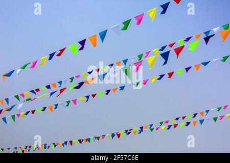 triangular holiday multi colored flags are suspended on a tight string outdoors park against the background of the sky, nobody. Stock Photo