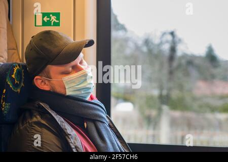 Sleeping man with medical protective mask on train Stock Photo