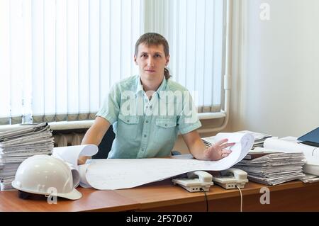 Architect or designer qualified in structural design working on the detailed project report in an office, looking at camera Stock Photo