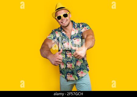 Young sportve man on vacation wearing floral summer shirt over yellow background success sign doing positive gesture with hand, thumbs up smiling and Stock Photo