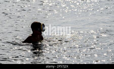 A guy dressed with a diving mask in the sea. A young man with a diving mask in the water. Concept: vacation, summer, sports, travel, lifestyle. Stock Photo