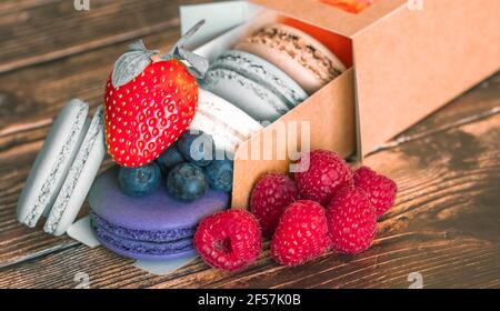 Handmade baking macaroon cookies in a gift box with fresh blueberries, raspberries and strawberries Stock Photo