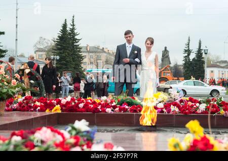 Petrozavodsk, Russia-circa May, 2010: Newlywed couple with members of the wedding stand close to war memorial with eternal light. Russian wedding day Stock Photo