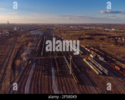 Drone shot over a railway sorting station with trains at sunset. Photo railway tracks with wagons, top view. Aerial top view. Stock Photo