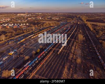 Drone shot over a railway sorting station with trains at sunset. Photo railway tracks with wagons, top view. Aerial top view. Stock Photo