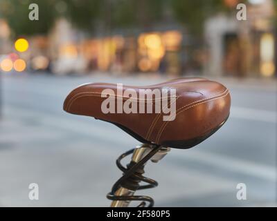 detail of a worn brown leather seat of a bicycle on a public street Stock Photo