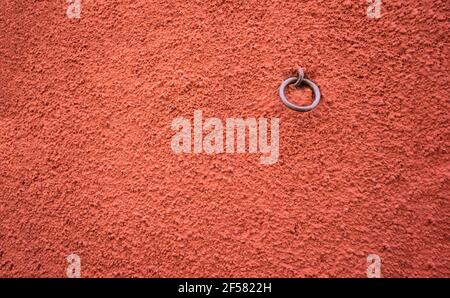 terracotta colored rough granulated paint texture, gotele, wine color, russet, reddish or tile color with a metal ring embedded in it, horizontal Stock Photo