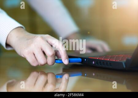 Hand  of woman connecting a Flash Drive to laptop computer on desktop for copy or transfer data. Stock Photo
