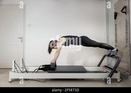 A woman doing pilates exercises on a reformed bed Stock Photo - Alamy