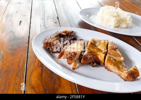 Grilled chicken and sticky rice in a white plate on a wooden table. Stock Photo