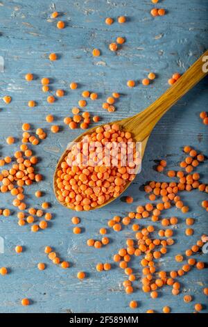 Red lentils in wooden spoon on blue wooden background. Top view. Stock Photo