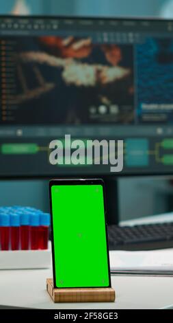 Display phone with green screen, mock up on template placed on desk in scientific lab while team of medical researcher scientists analysing virus evolution at digital monitor conducting experiment Stock Photo