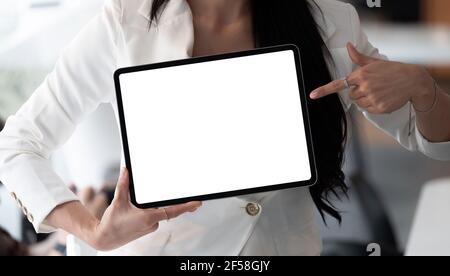 Businesswoman shows the digital tablet with blank screen in a front view shot. Stock Photo
