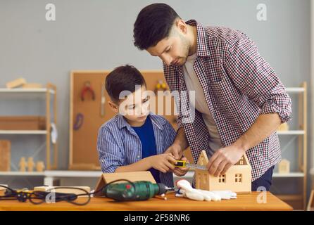 Little boy and his dad making wooden house model as part of school homework project Stock Photo