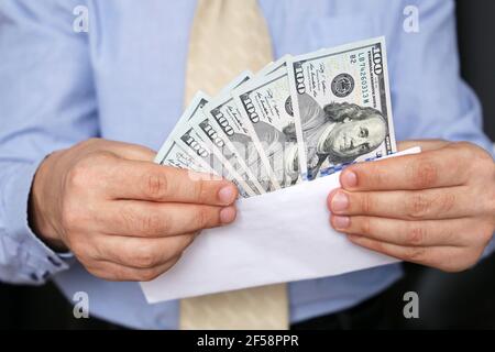 US dollars in male hands close up, man in business clothes with money in white envelope. Concept of cash, income, bribe or salary Stock Photo