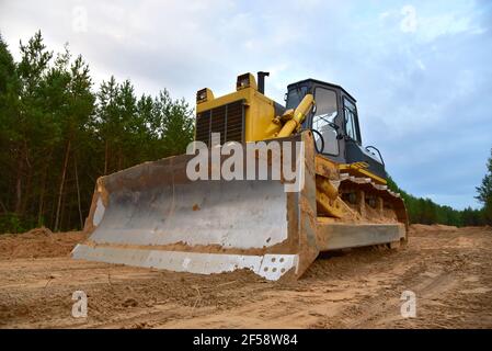 Dozer during clearing forest for construction new road . Yellow Bulldozer at forestry work Earth-moving equipment at road work, land clearing, grading Stock Photo