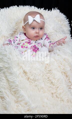 Beautiful baby in a fur blanket. The girl is four months old. Children under one year old. Stock Photo