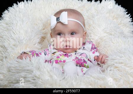 Beautiful baby in a fur blanket. The girl is four months old. Children under one year old. Stock Photo