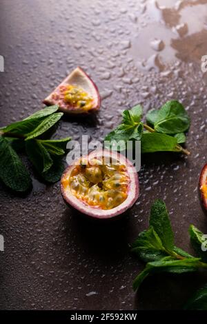 tropical fruit passion fruit on a dark background with water droplets and mint leaves. copyspace Stock Photo