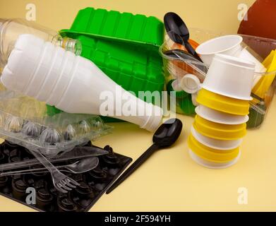 Waste sorting. Plastic waste for recycling. Bottles, containers, forks, spoons, egg packaging, lids. Yellow background. Environmentally friendly - no waste. Zero waste is a trend. Stock Photo