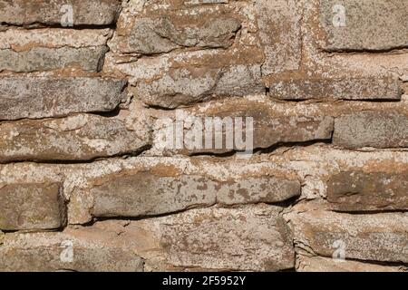 Stone wall pattern of sandstone with mortar between rough stone shapes Stock Photo
