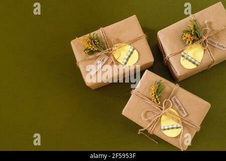 Easter flat lay zero waste, gift boxes with an egg-shaped tag and decorated with flowers. Space for text. top view on green background Stock Photo