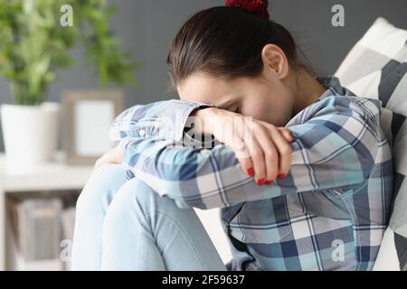Sad woman sitting with her head bowed on sofa Stock Photo