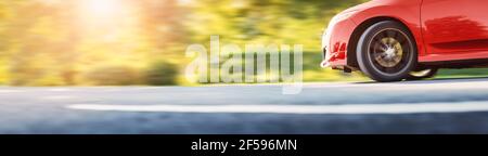 Red car moving on asphalt road on summer day. Stock Photo