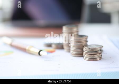 Coins and ballpoint pen lying on document with graph closeup Stock Photo