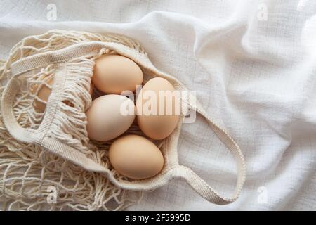 Chicken eggs in a string bag on white background, selective focus. Happy easter background. Stock Photo