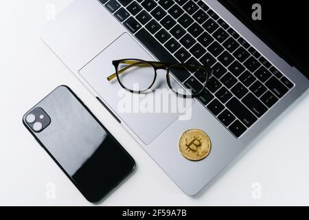 Office work area golden coins Bitcoin laptop Mobile phone Glasses. Concept of Bitcoin Cryptocurrency Trading Stock Photo